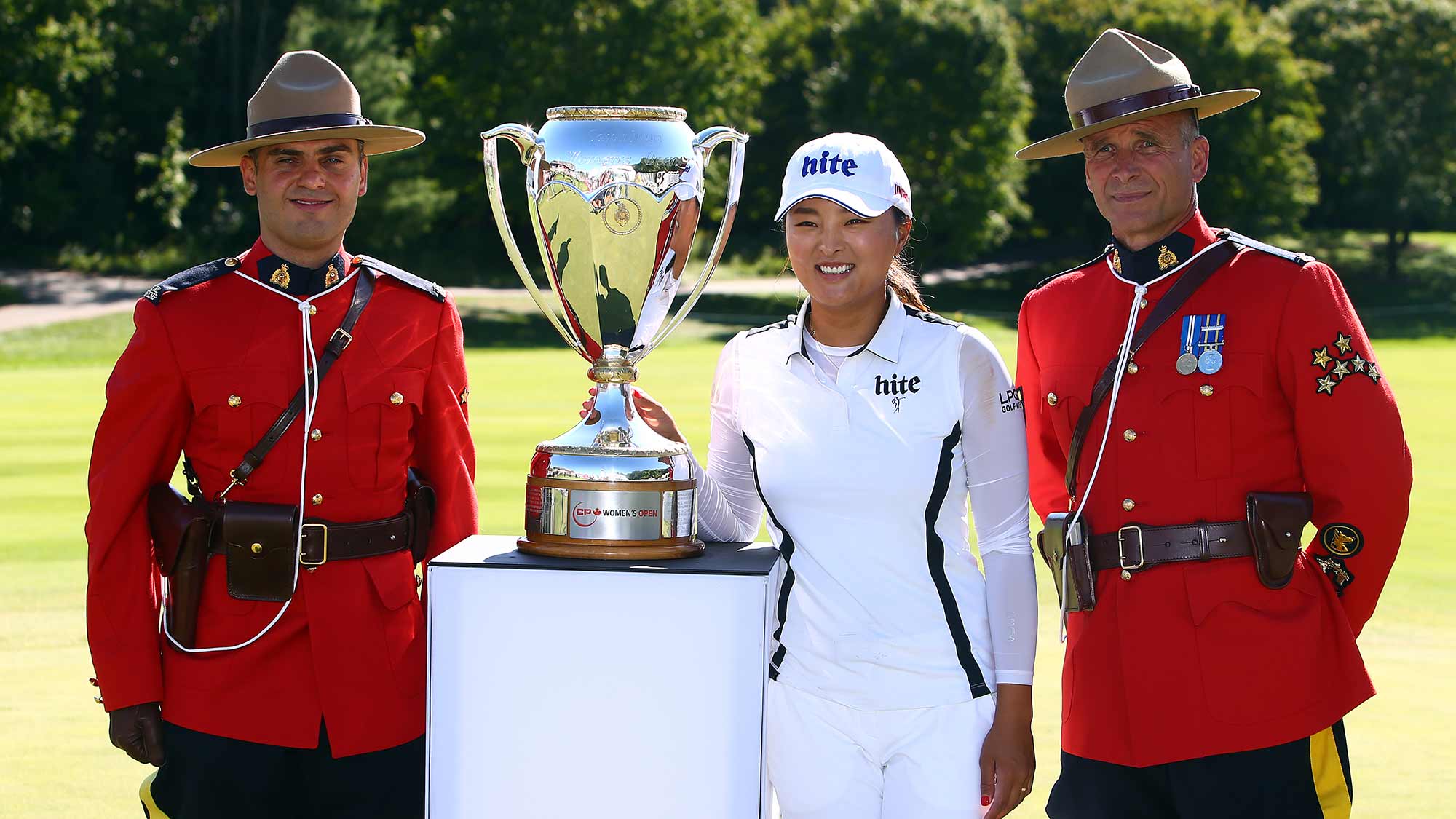  Jin Young Ko of Korea poses with the CP Women's Open Championship Trophy and Canadian Mounties following the final round at Magna Golf Club on August 25, 2019 in Aurora, Canada